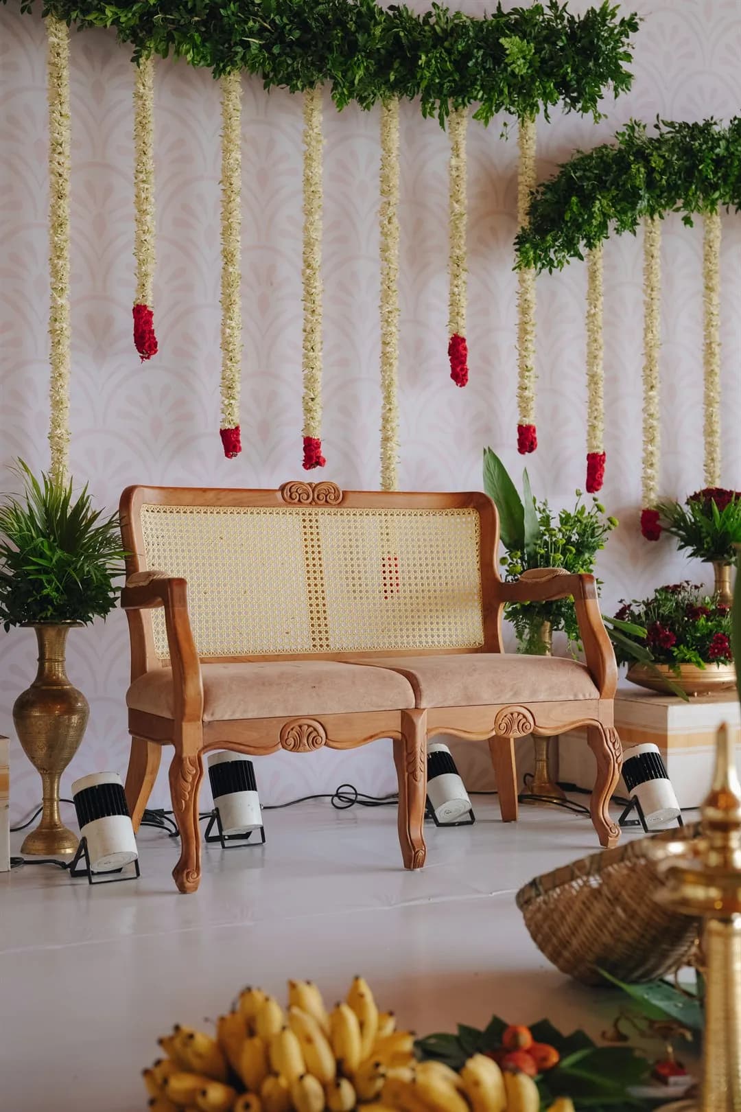 Carved wooden settee framed by jasmine and rose garlands